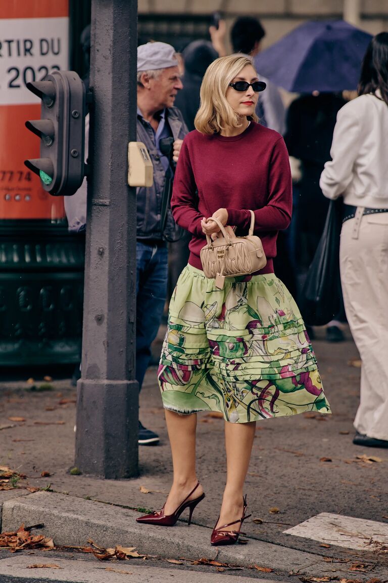 paris fashion week guest wearing a maroon red sweater and green floral skirt