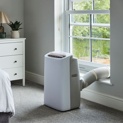 The new Meaco Cirro portable air conditioner vented out of a window in a neutral bedroom environment