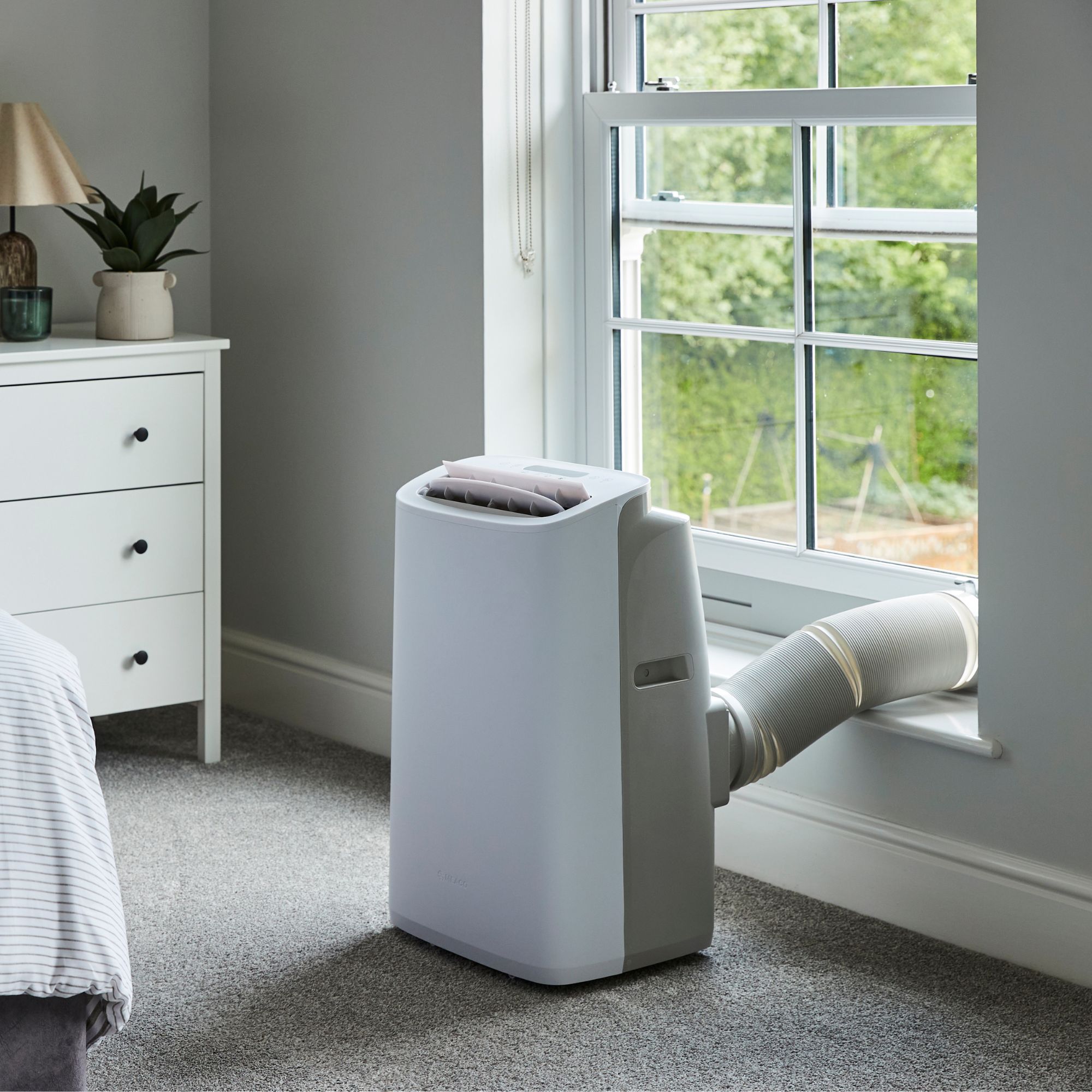 The new Meaco Cirro portable air conditioner vented out of a window in a neutral bedroom environment