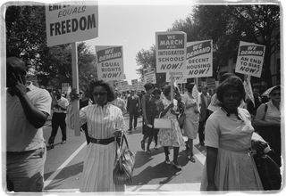 African-Americans carrying signs for equal rights, integrated schools, decent housing and an end to bias during the 1963 March on Washington.