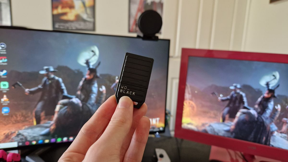 WD Black C5 held in front of two gaming monitors with its shield cover on