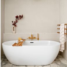 white freestanding bath in front of a beige wall with a brown towel rail
