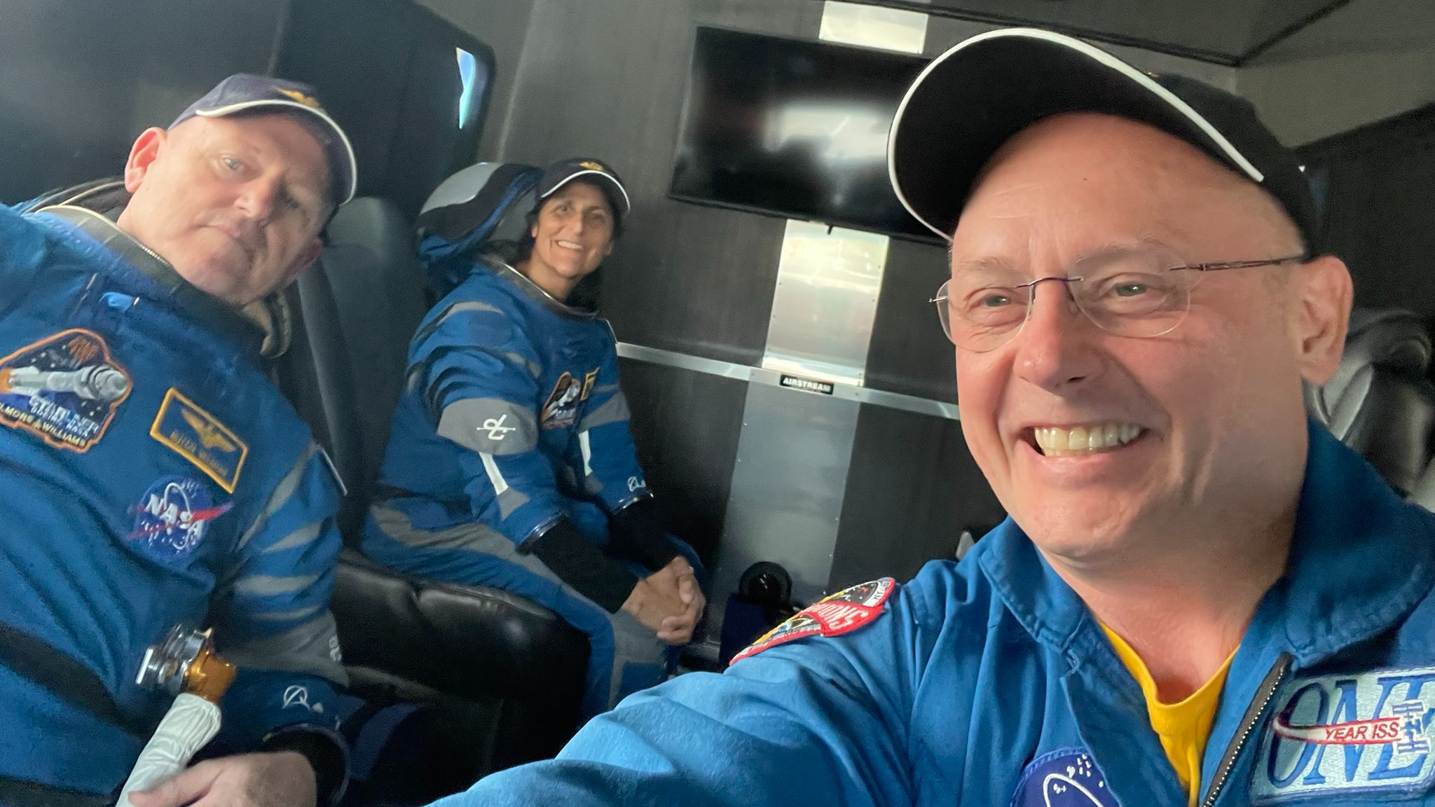 Drie NASA-astronauten in een vrachtwagen glimlachend naar de camera