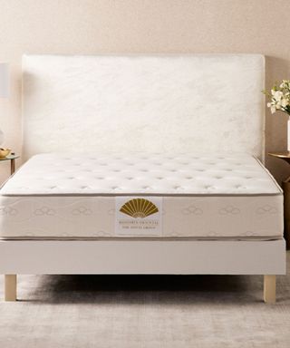 Mandarin Oriental Mattress on a white bed frame against a cream wall. 