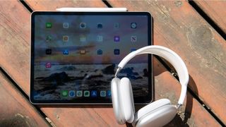 An iPad Pro on a table next to a pair of headphones 