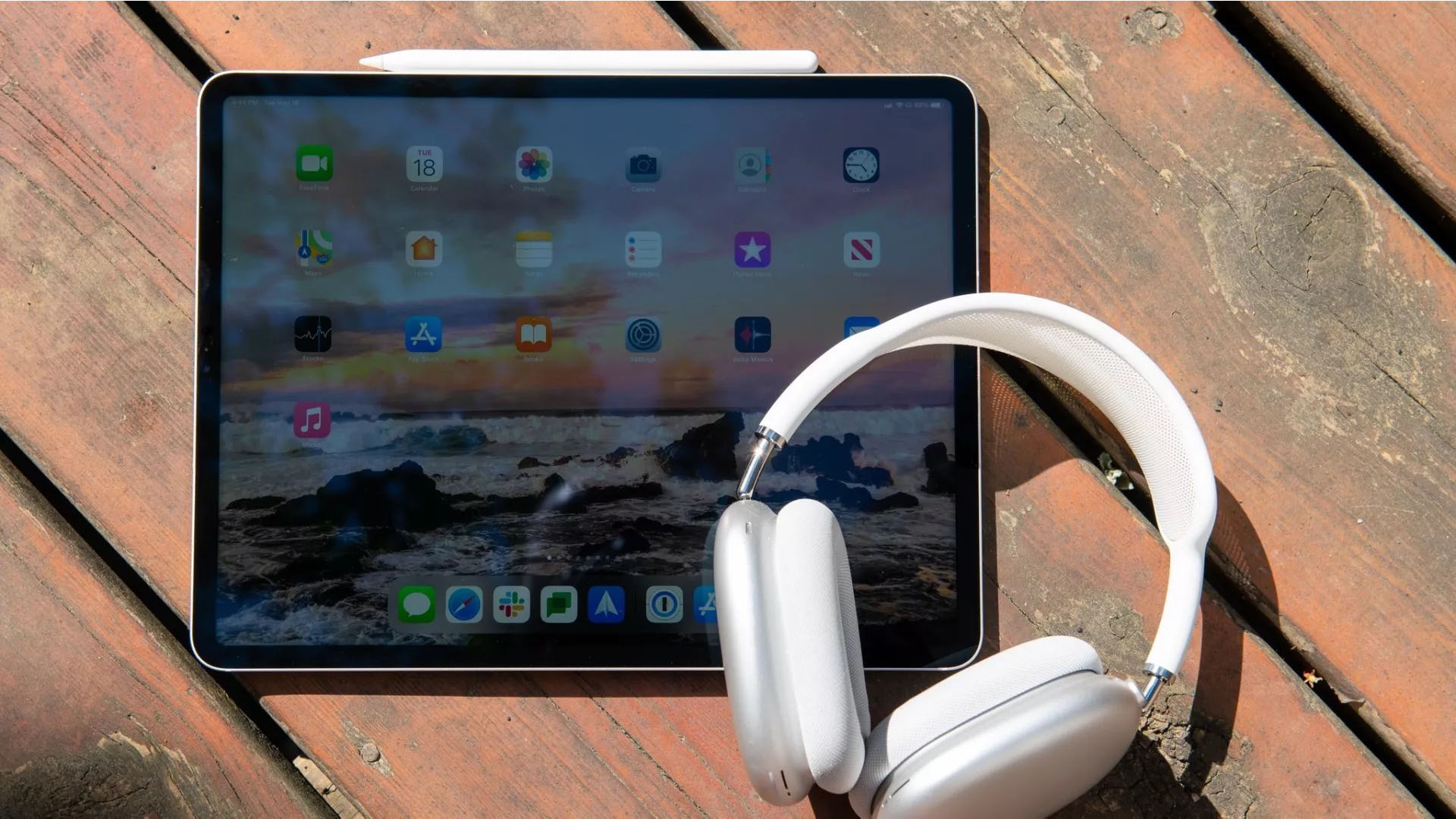 An iPad Pro on a table next to headphones