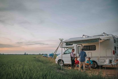 People standing next to a RV at sunset