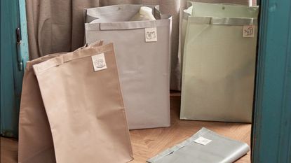 pastel-toned recycling bags placed on a wooden floor