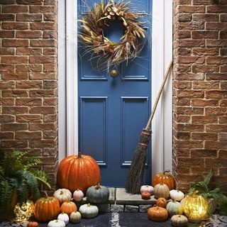 blue front door with pumpkins and autumn wreath