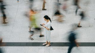 woman stressed looking at her phone within a busy crowd