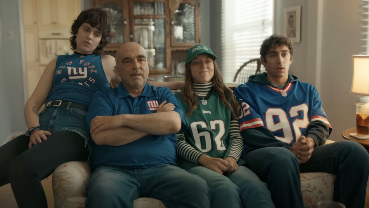 Family of Giants and Eagles fans watching the game in living room for NFL Sunday Ticket commercial.