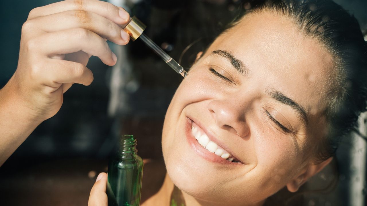 a woman applies the best tanning drops with a dropper