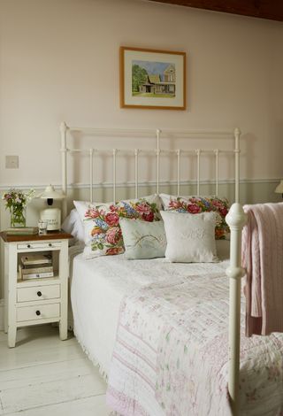 metal-framed-vintage-bed-with-bedside-table-floral-cushions