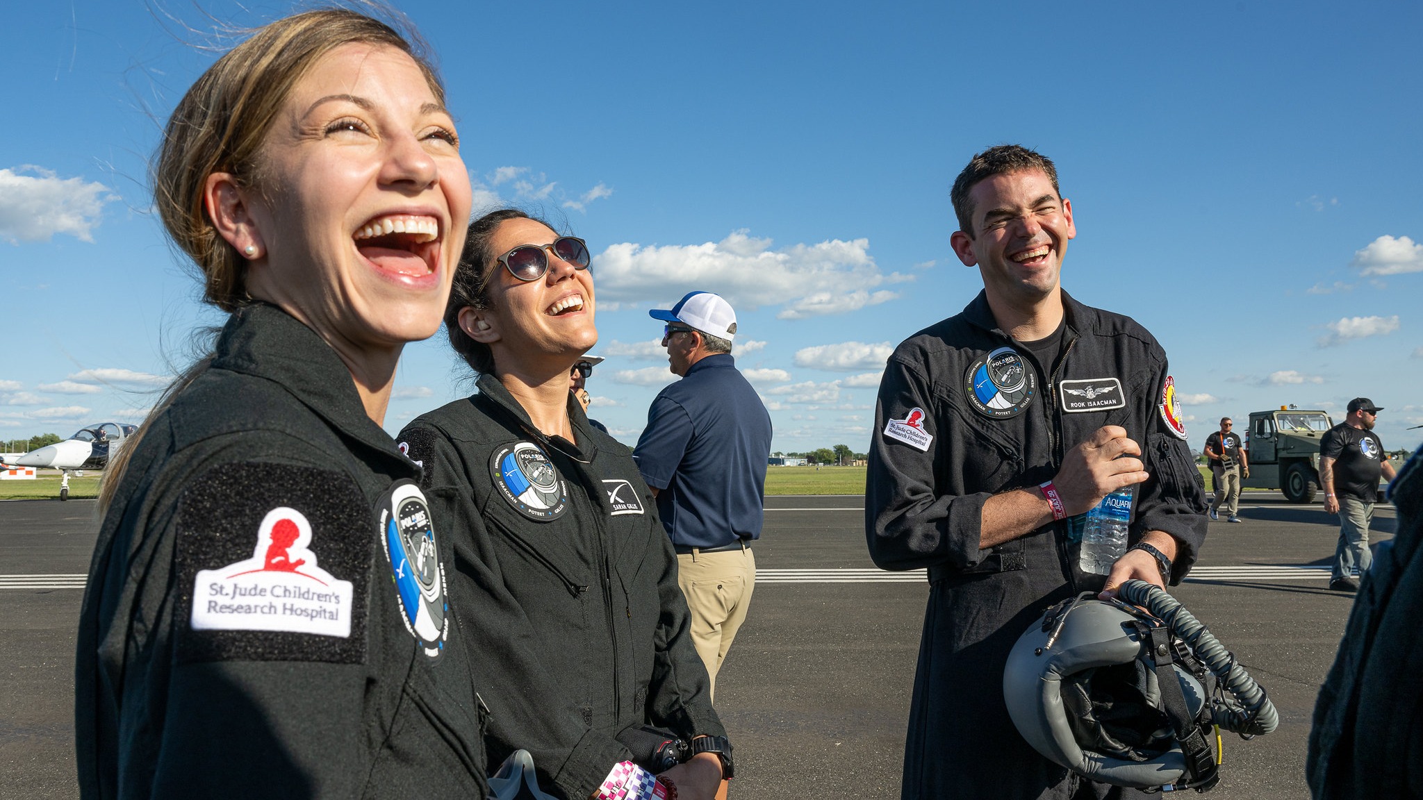 three crew members of polaris dawn laughing inside black flight suits
