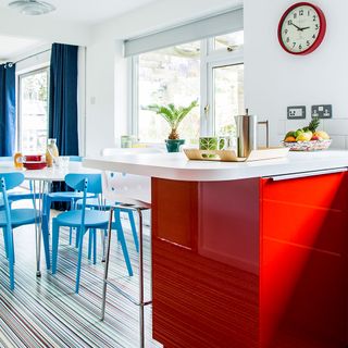 dinning area with white wall white and red counter designed floor white table and blue chairs