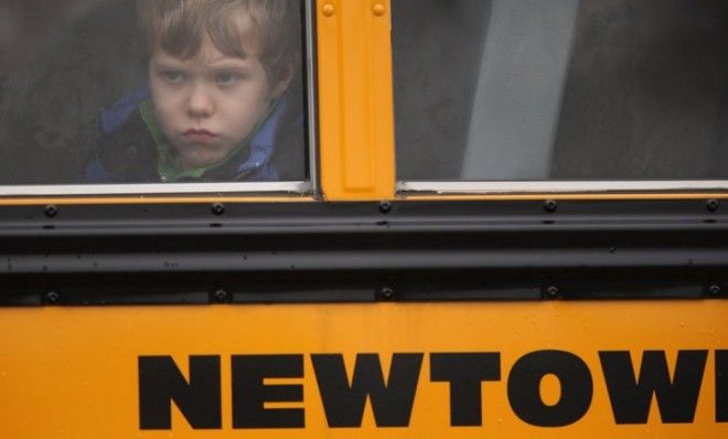 A child gazes from a school bus as it passes by a Newtown, Conn., church on Dec. 18, where a funeral service for a Sandy Hook victim was being held. 