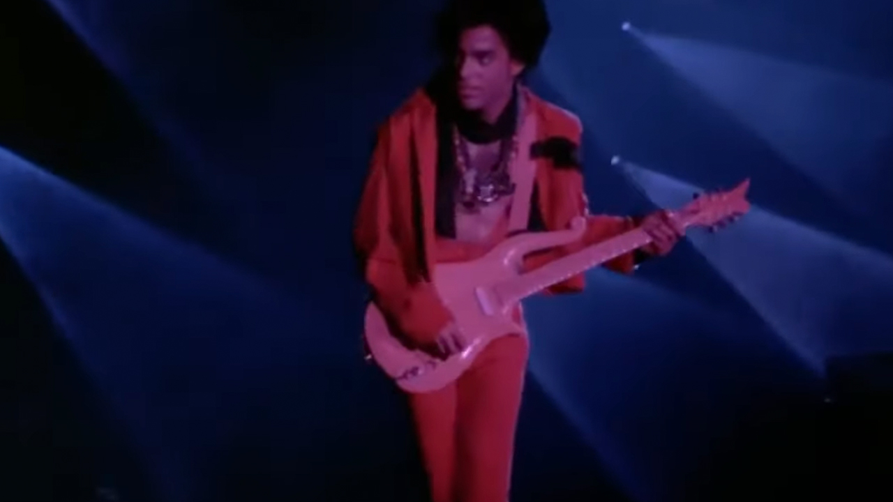 Prince playing guitar in a pink suit