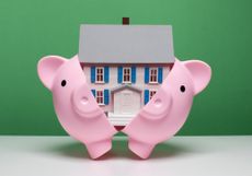 piggy bank breaking open to reveal a miniature house