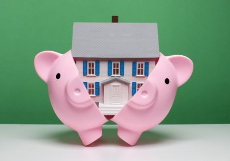 piggy bank breaking open to reveal a miniature house