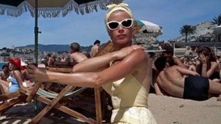 Grace Kelly applies sunscreen while sitting on the beach in To Catch A Thief.