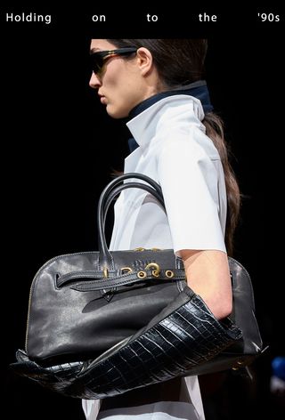 a close runway photo of a model on Miu Miu's fall runway carrying a '90s bowler handbag