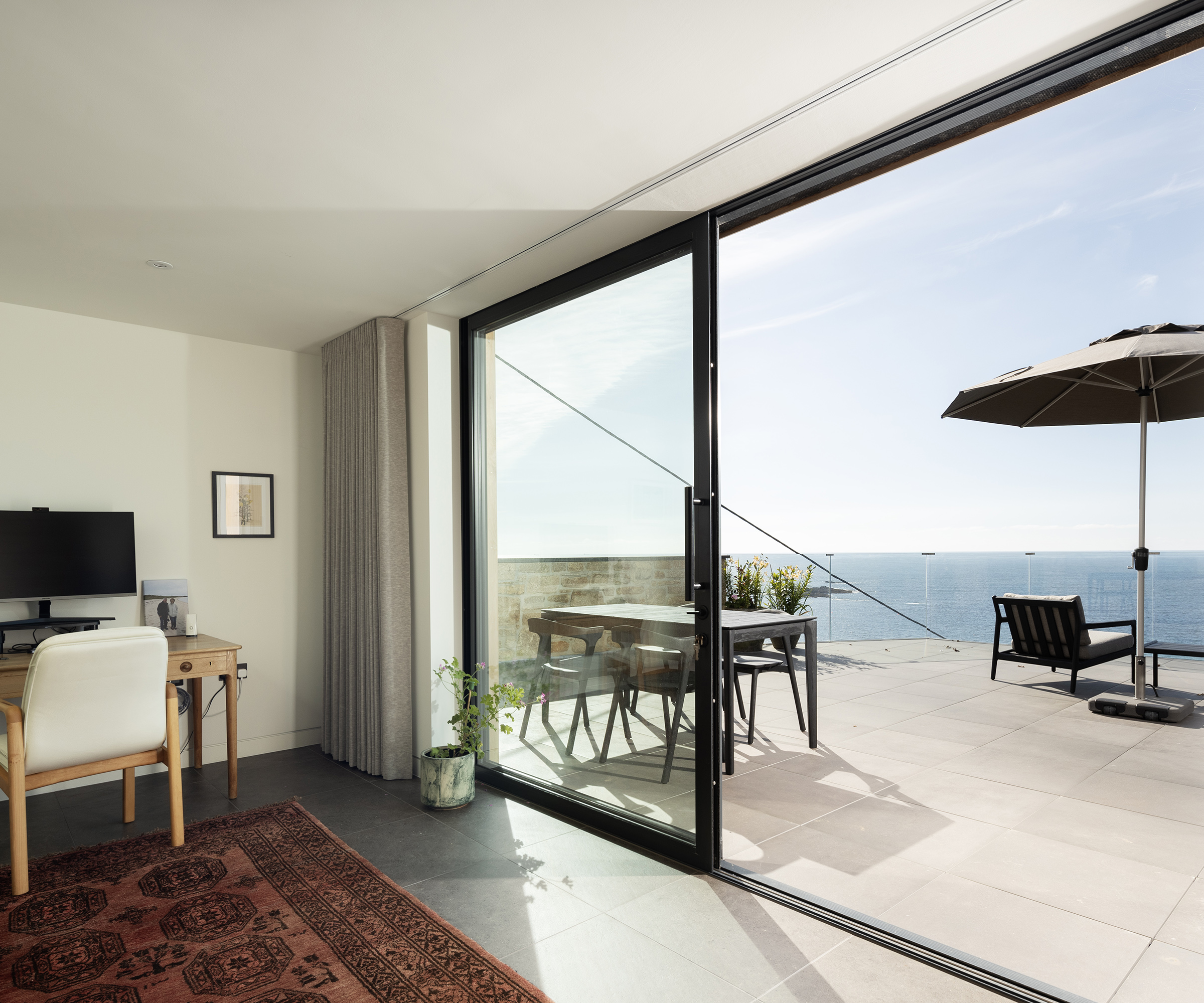 Sliding doors looking out onto a sunny terrace with sea views
