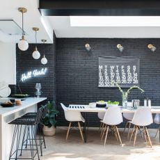 Black painted brick wall in the dining area of a kitchen extension, with white dining table and chairs