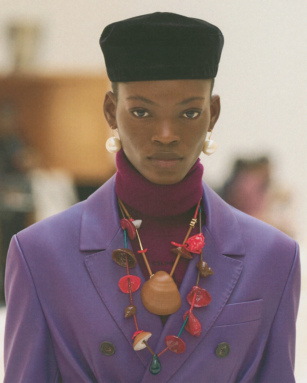 a model on the celine fall 2026 runway wearing a purple trench with shell necklaces and a black beret