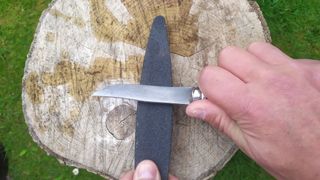 Demonstrating how to sharpen a camping knife on a whetstone