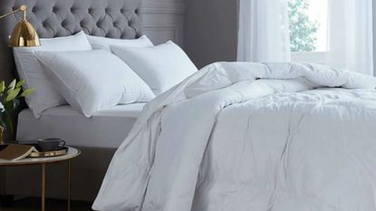 White bedding on grey bed with gold bedside lamp from DUSK 