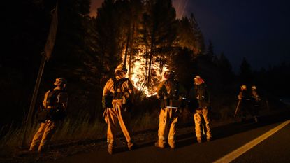 Firefighters standing in front of a wildfire