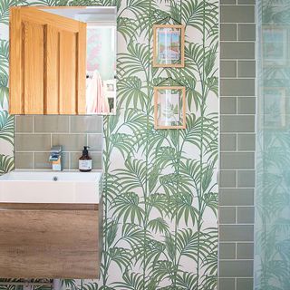 bathroom with green leaves designed wallpaper and wash basin