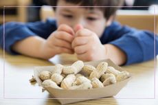 Little boy eating from a box of peanuts