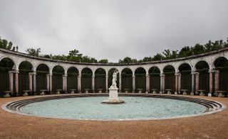 Circular water feature with curved arched architecture in background