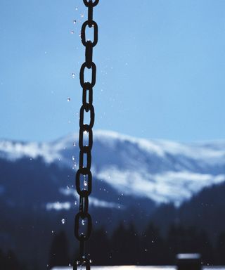 A frozen rain chain in a snowy environment