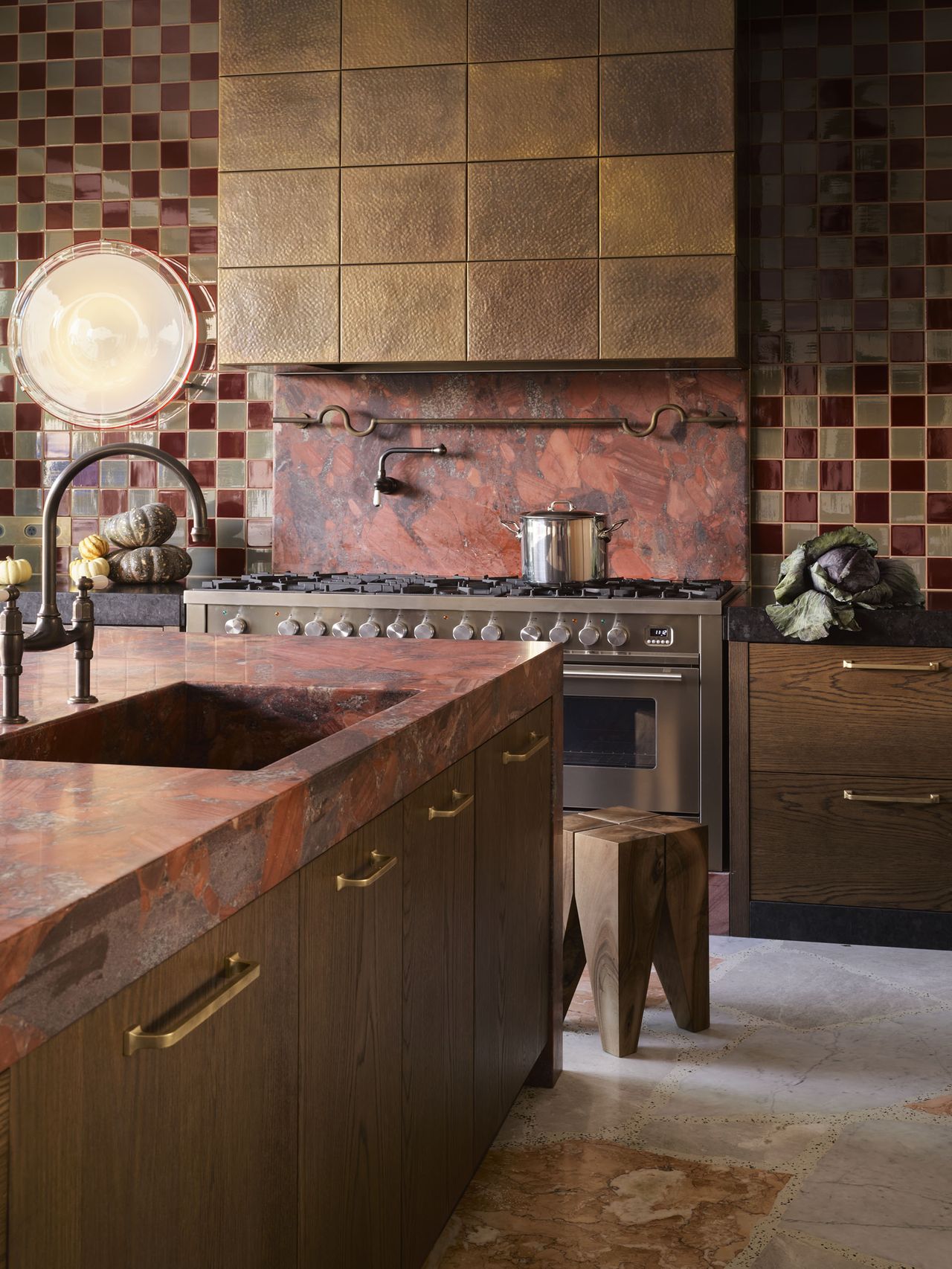 modern rustic kitchen with checkered wall tile, red marble countertop, marble floors, gold clad rangehood