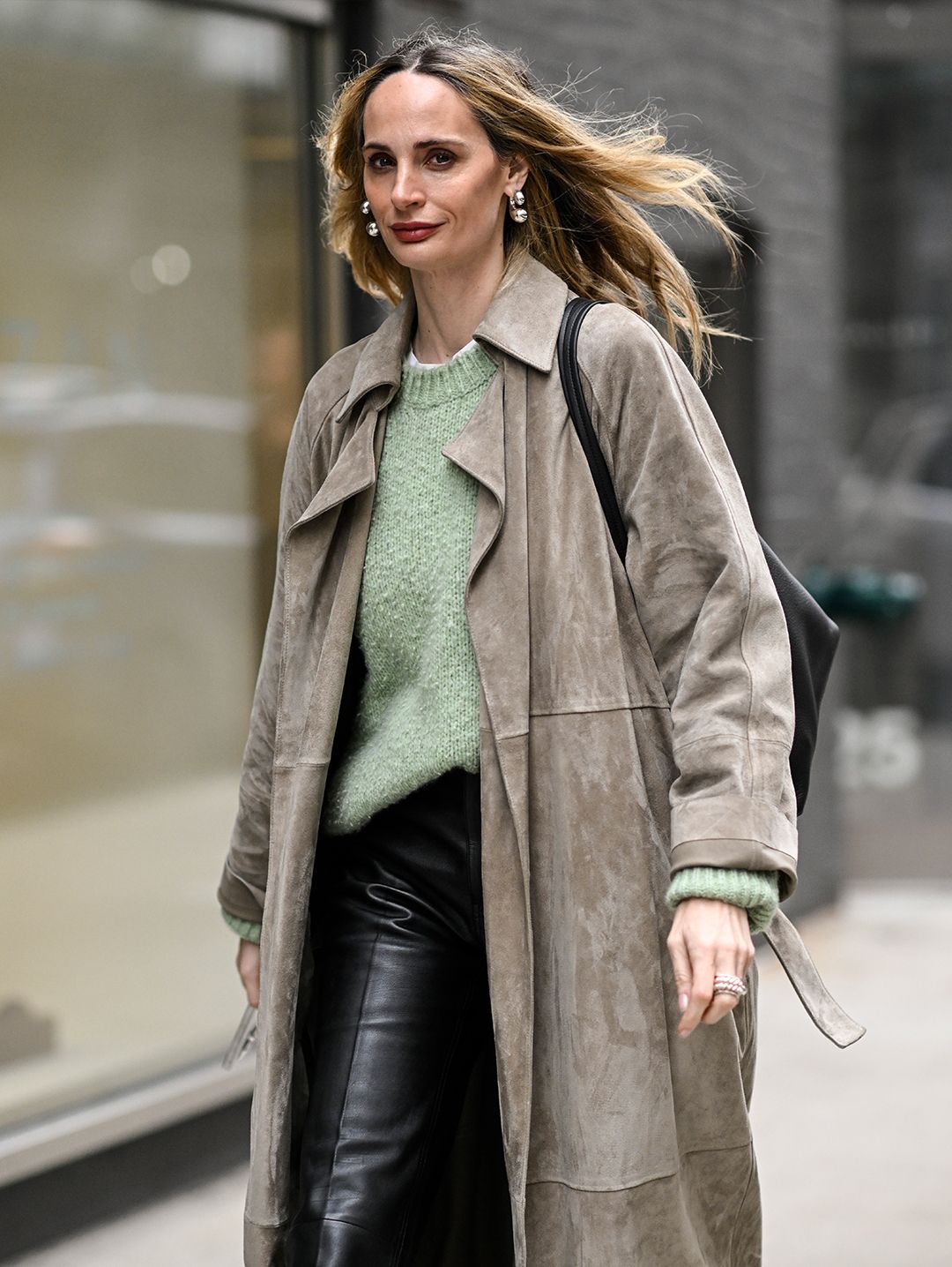 Lauren Santo Domingo wearing a suede trench coat over a green sweater and leather pants.