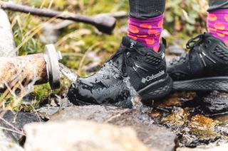 Hiker's feet wearing the Columbia Konos TRS outdry Mid Hiking Shoe in a stream