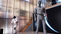 A spacesuit in the background and an undersuit in the foreground on mannequins. 