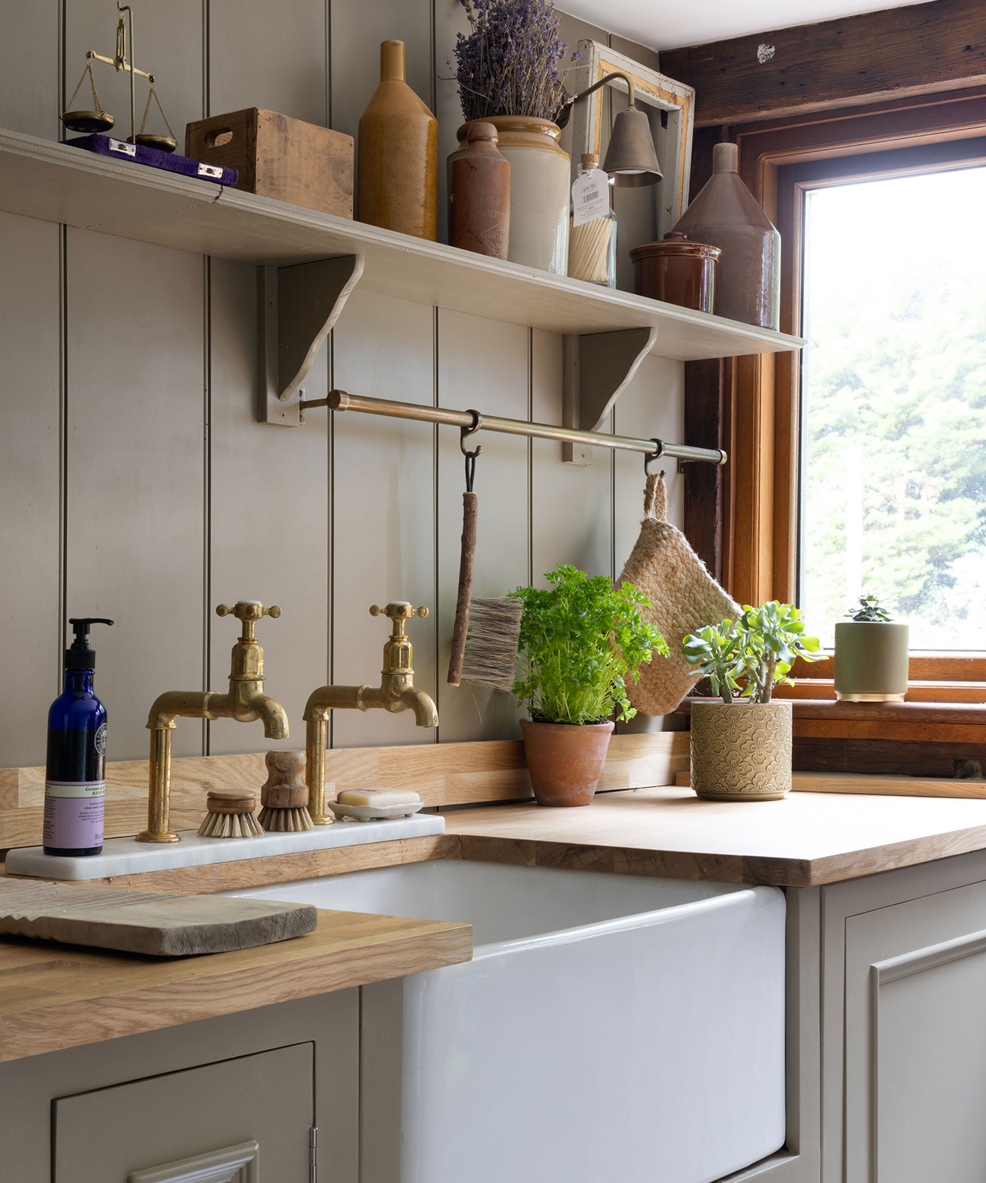 small utility room with wooden wall panelling and Belfast sink with brass pillar taps