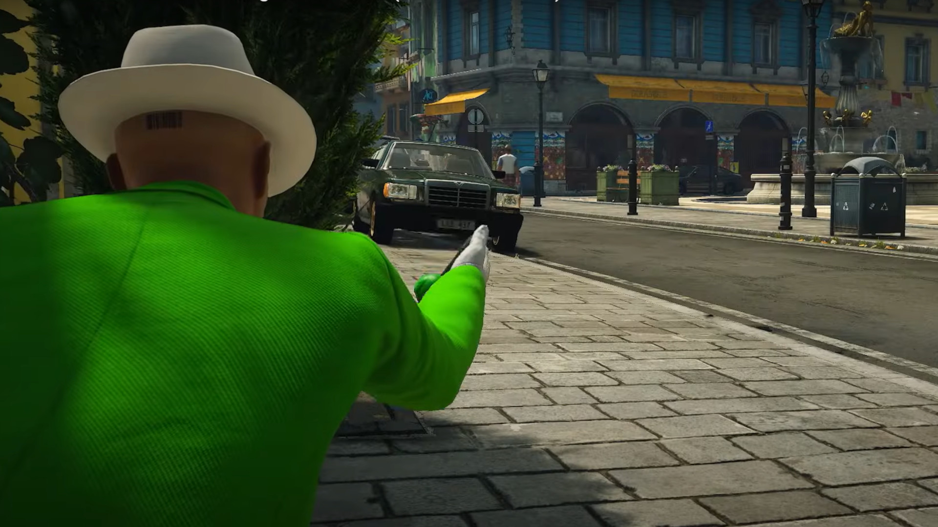 Agent 47 holding a gun while wearing a bright green suit during the trailer for the Switch 2 launch game, Hitman World of Assassination – Signature Edition.