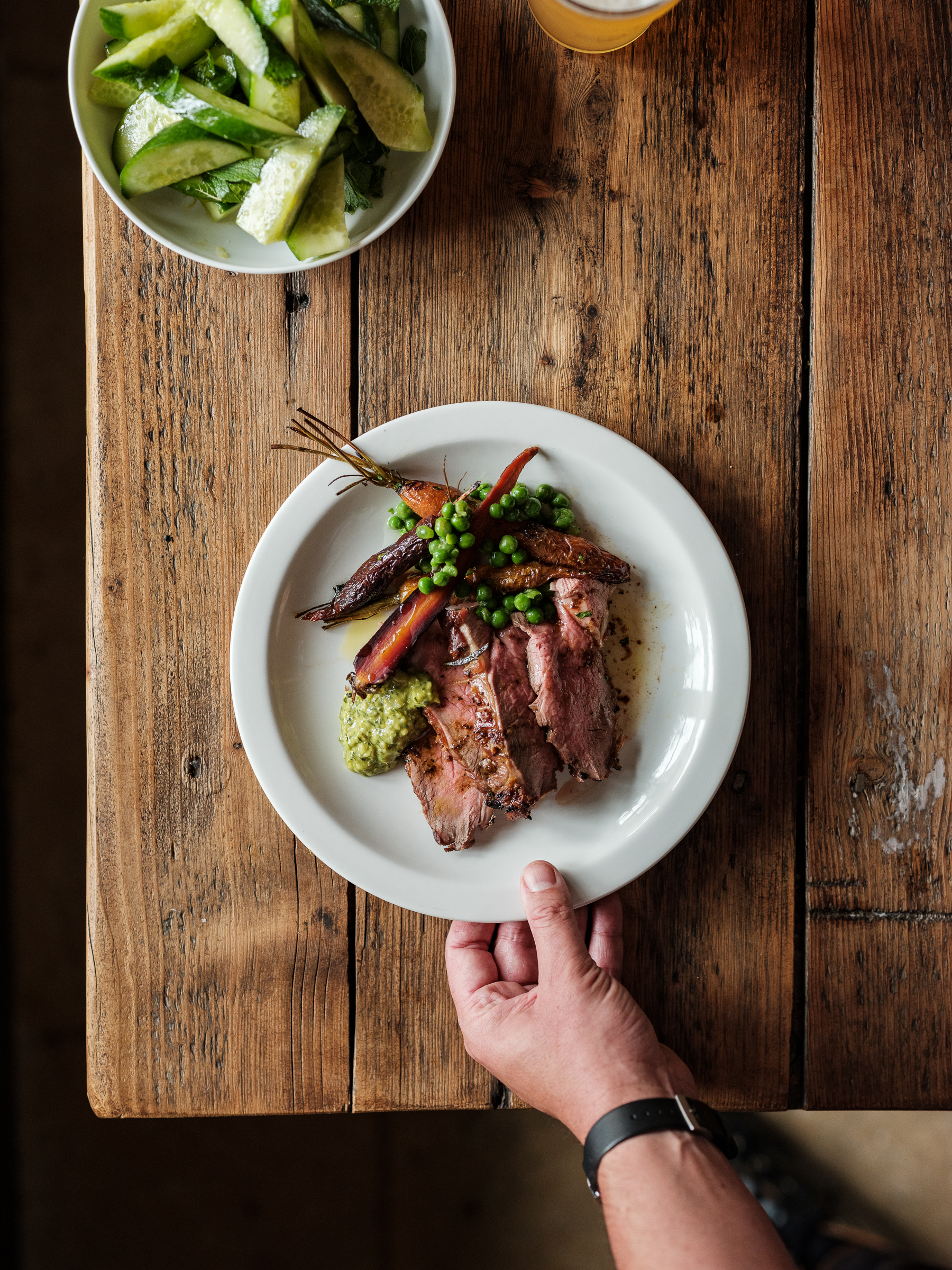A plate of lamb and vegetables served with a pint and thickly cut cucumber at The Bull in Charlbury
