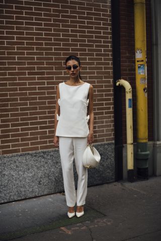 woman wearing white top, white trousers, and white heels