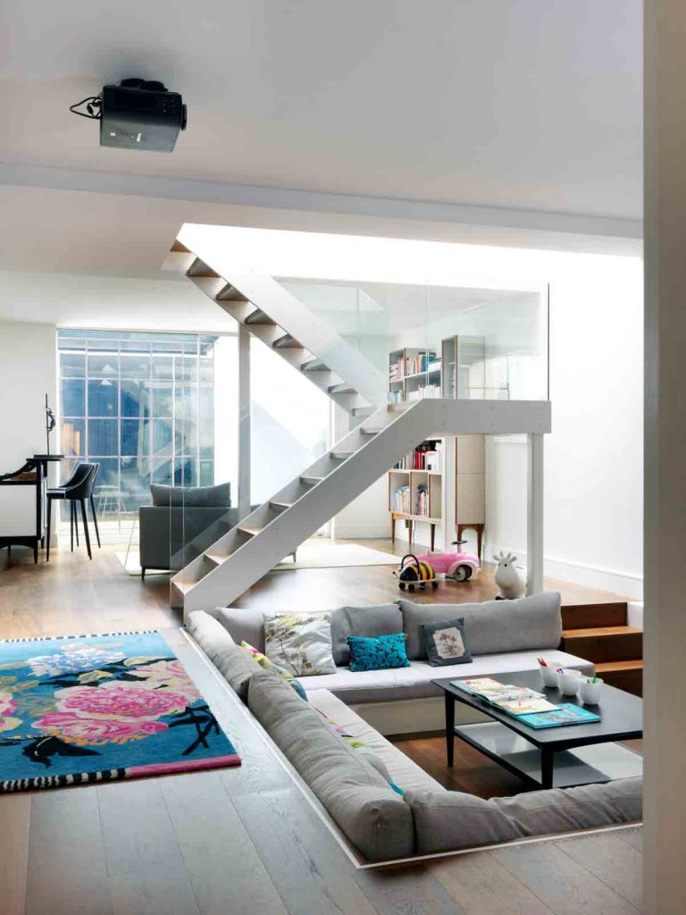 staircase with glass banister leading into basement lounge