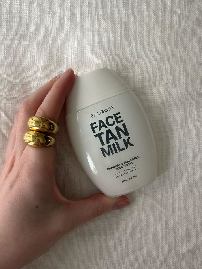 Die stellvertretende Beauty-Redakteurin Grace Lindsay hält die Bali Body Face Tan Milk in der Hand