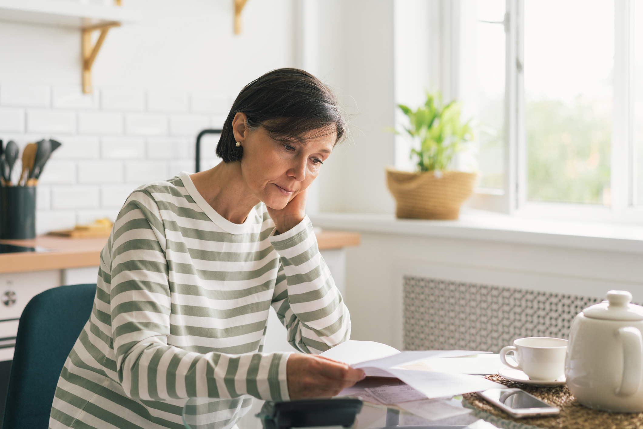 Woman looking at insurance documents at her kitchen table.
