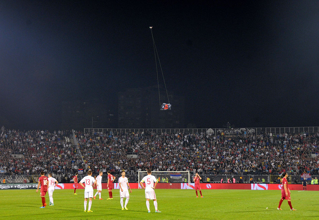 A flag with Albanian national symbols attached to a remotely operated drone flies in the stadium during brawl between players on the pitch during the UEFA EURO 2016 group I qualifying soccer match between Serbia and Albania is abandoned in Belgrade, Serbia on October 14, 2014. Match officials abandon Tuesday's Euro 2016 qualifier between Serbia and Albania after a drone carrying an Albanian flag entered the stadium late in the first half and sparked a brawl between players and fans.