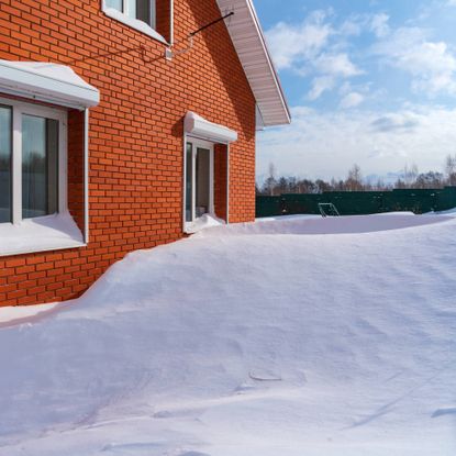 Snow drifts against a red brick house