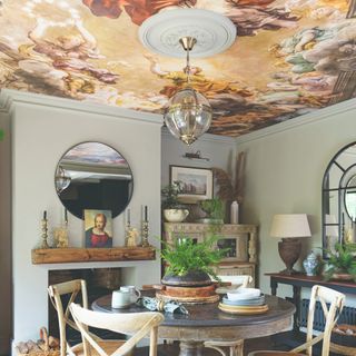 A renaissance-inspired painted ceiling in a dining room with a round dining table