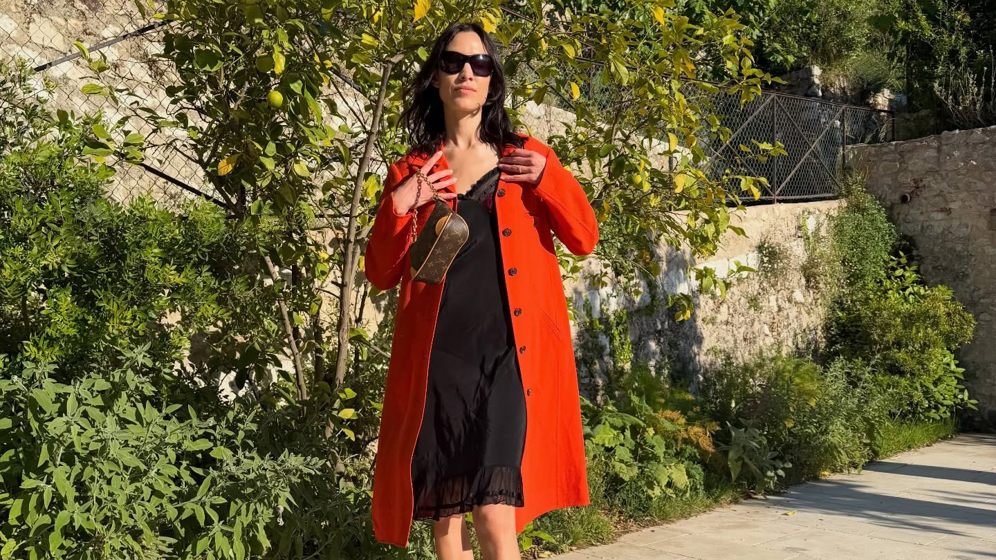 Alexa Chung wearing a red trench with a black slip dress, Louis Vuitton bag, and leopard-print Alaia thong high-heel sandals in France.